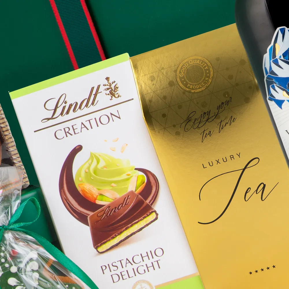 Szczegółowe ujęcie czekolady Lindt Creation Pistachio Delight oraz Czarnej japońskiej herbaty liściastej w złotym opakowaniu. Ekskluzywne słodycze w zestawie SU45.
